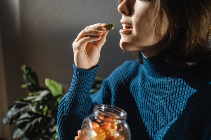 Person taking vitamin gummy from jar