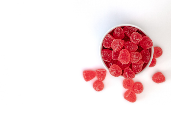Bowl of red gummy candies on white background.