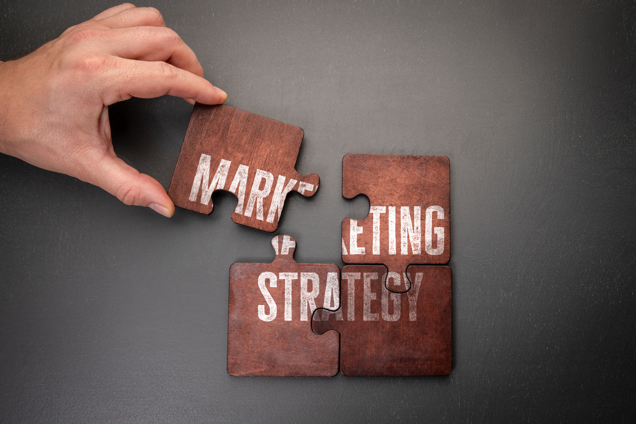 Hand completing marketing strategy puzzle.
