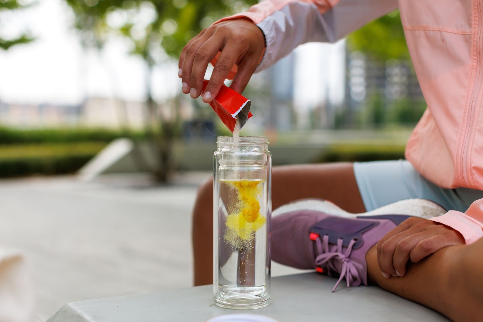 Person mixing drink powder into water outdoors